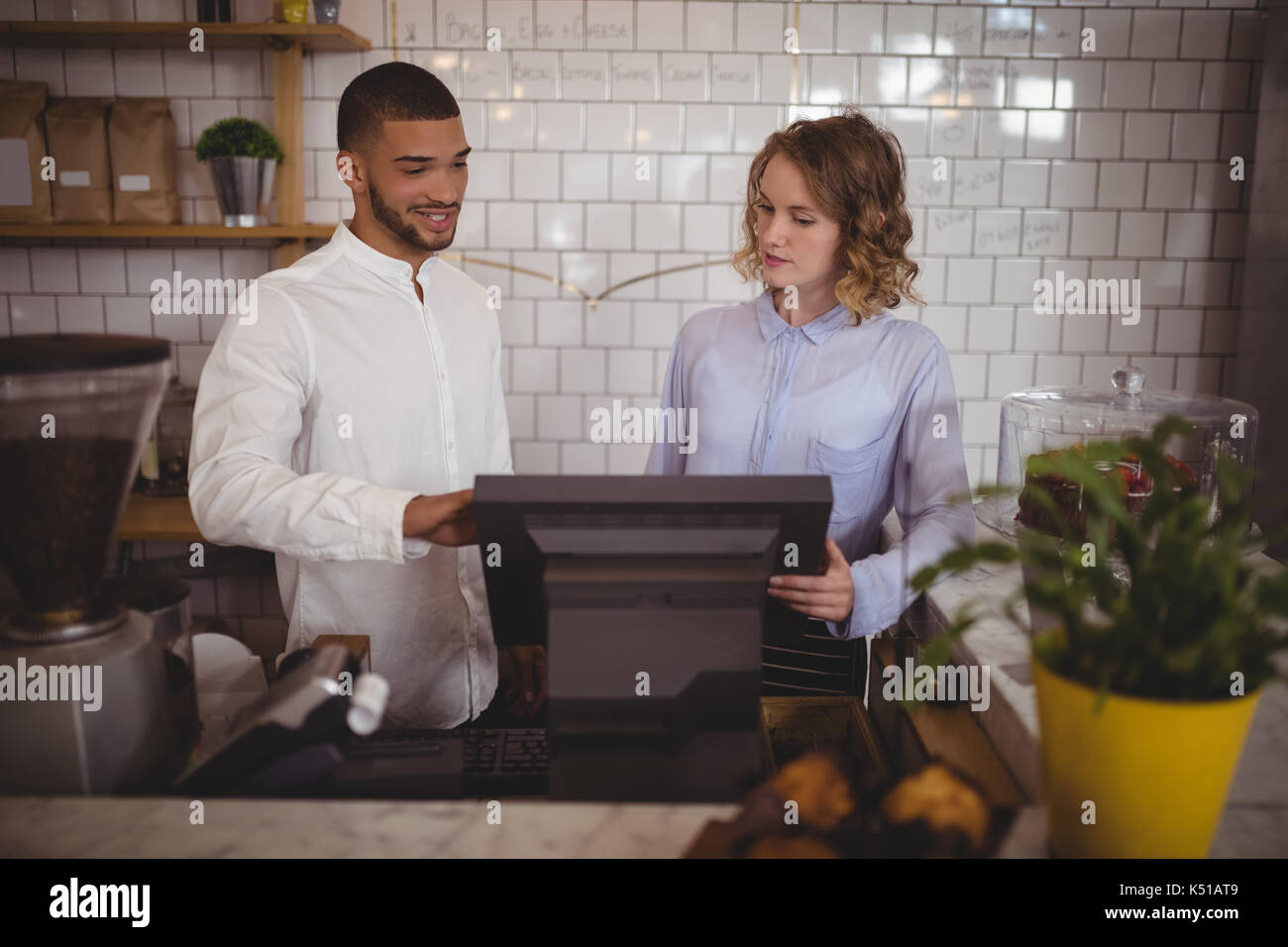 Männliche Besitzer mit Kellnerin mit Computer an der Theke im Café Stockfoto