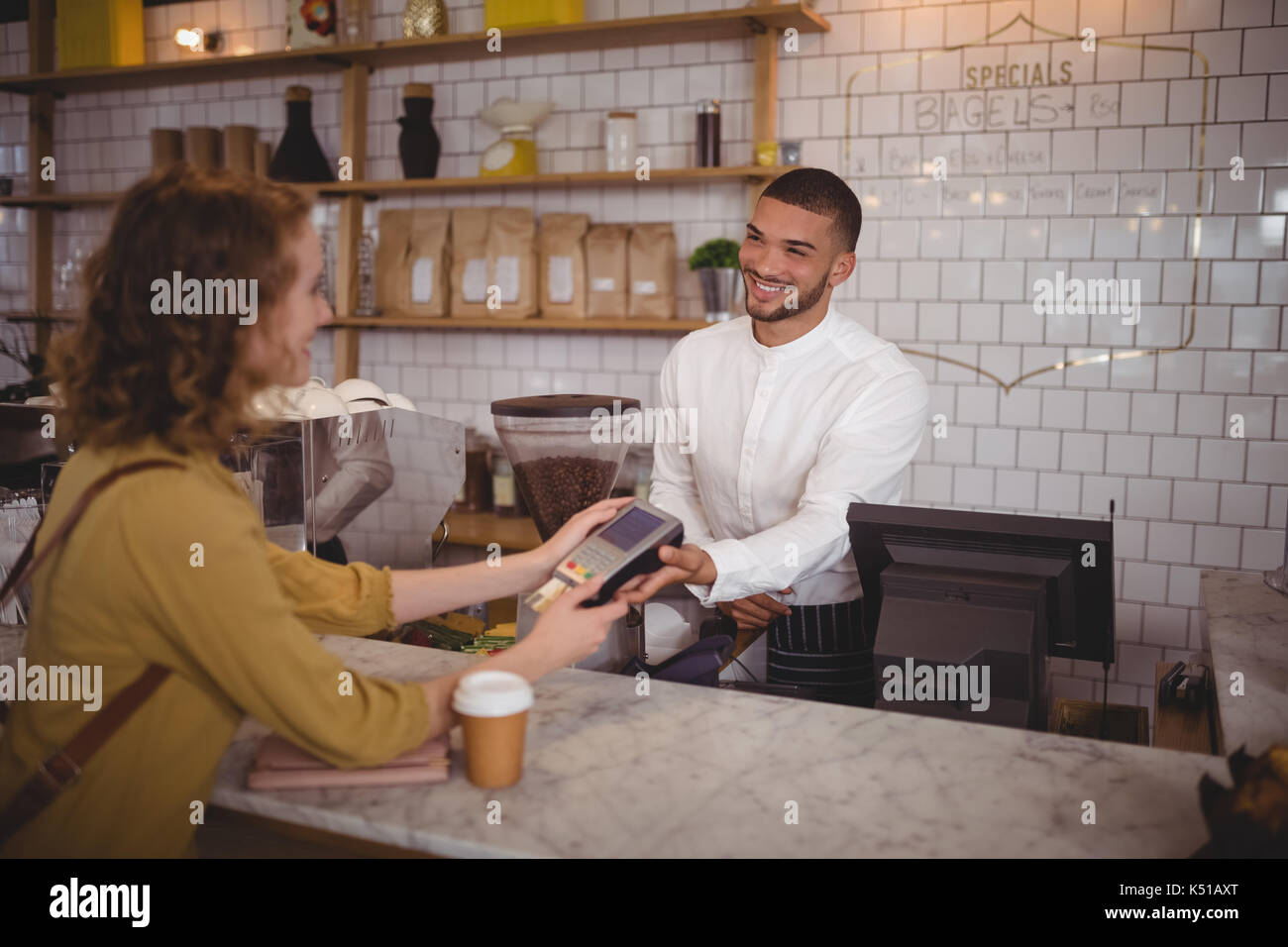 Lächelnden jungen Frau Zahlung durch Kreditkarte an der Theke im Café zu Kellner Stockfoto