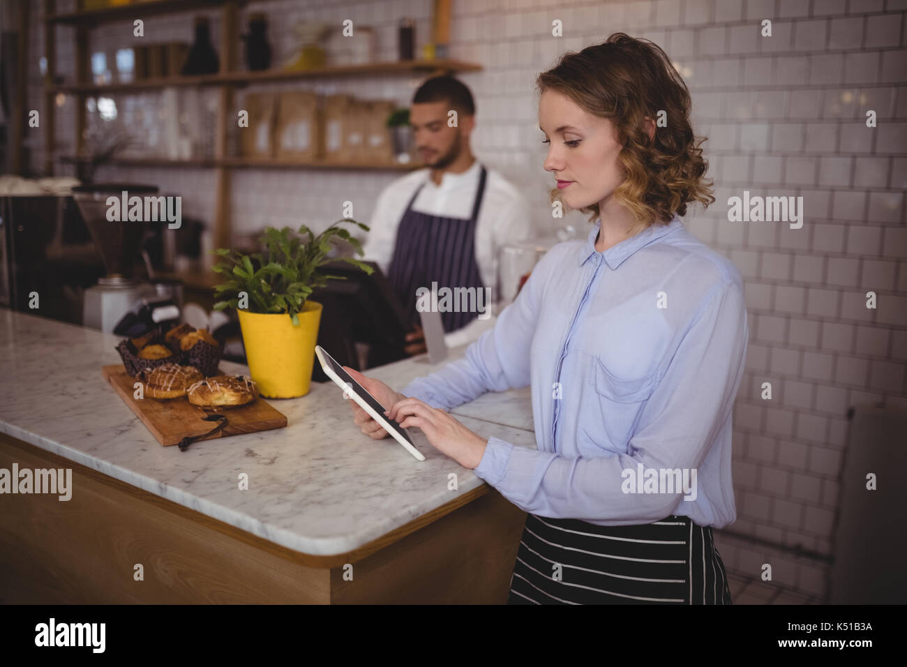 Junge Kellnerin mit Tablet Computer, während an der Theke im Café stehend Stockfoto