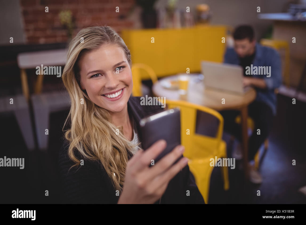 Portrait von lächelnden jungen attraktiven Frau mit Handy im Coffee Shop Stockfoto