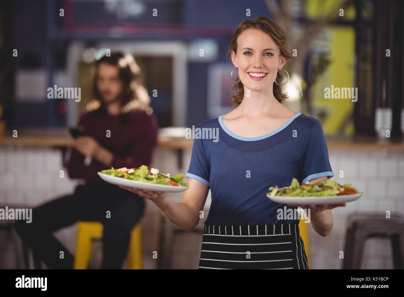 Portrait von lächelnden jungen Kellnerin mit frischem Salat Teller zum Coffee Shop Stockfoto