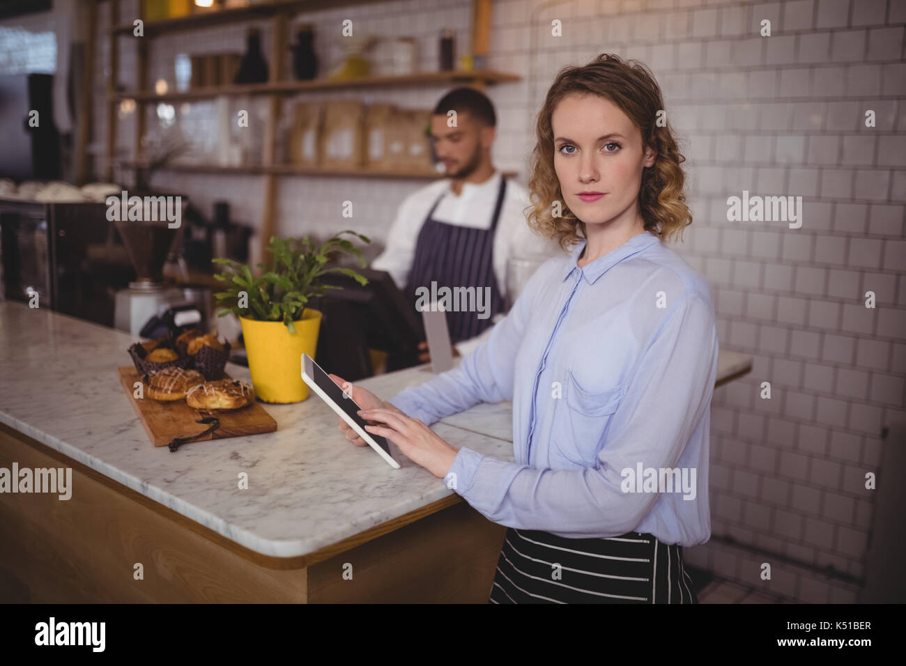 Portrait von zuversichtlich Kellnerin mit digitalen Tablet beim Stehen an der Theke im Café Stockfoto