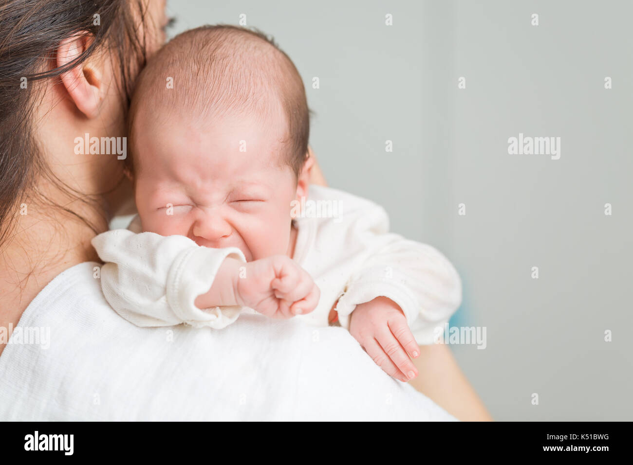 Neugeborenes im Schmerz schreiend mit Koliken auf Mutters Schultern Stockfoto