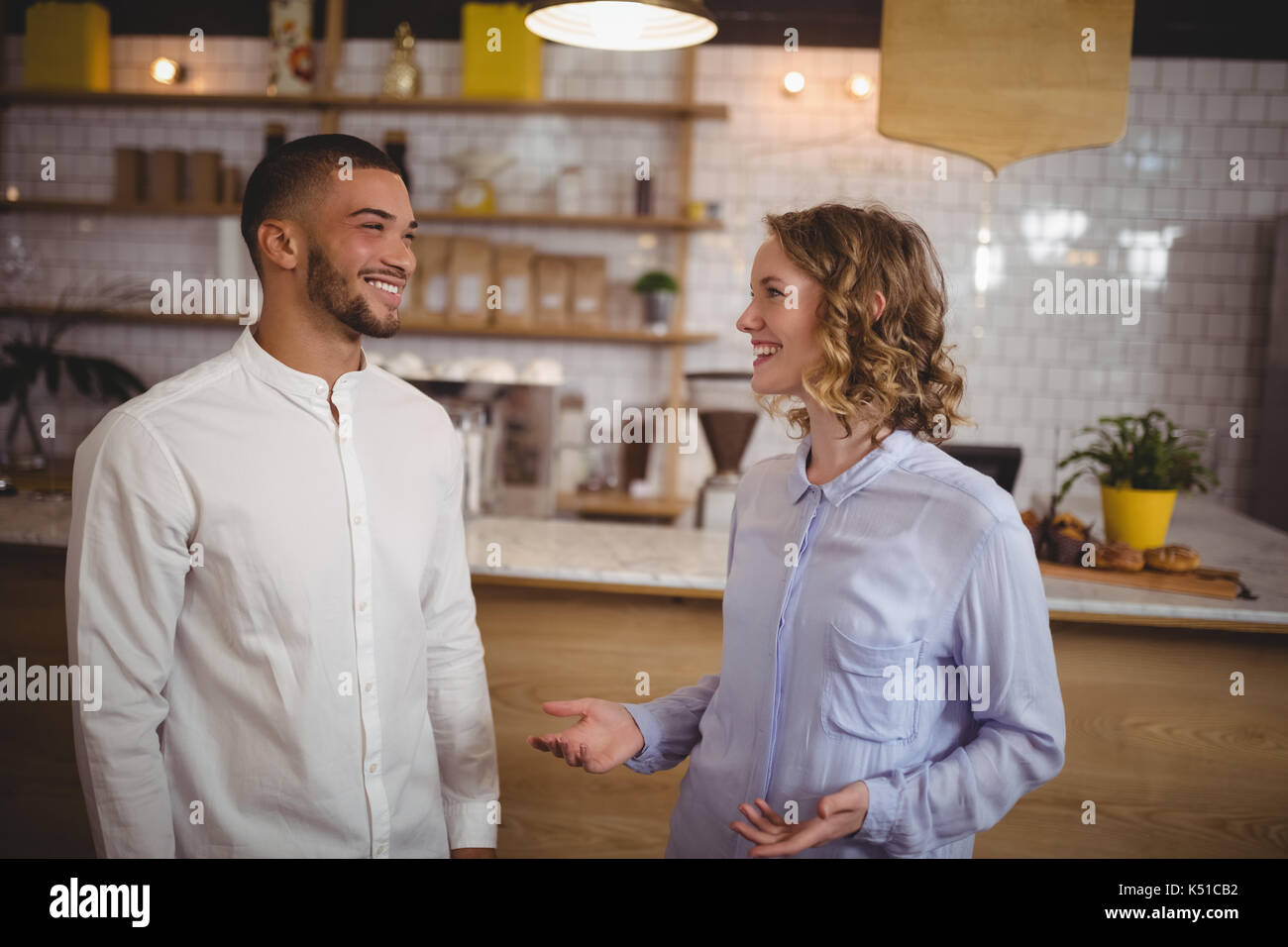 Lächelnden jungen Freunde sprechen, während man im Café Stockfoto