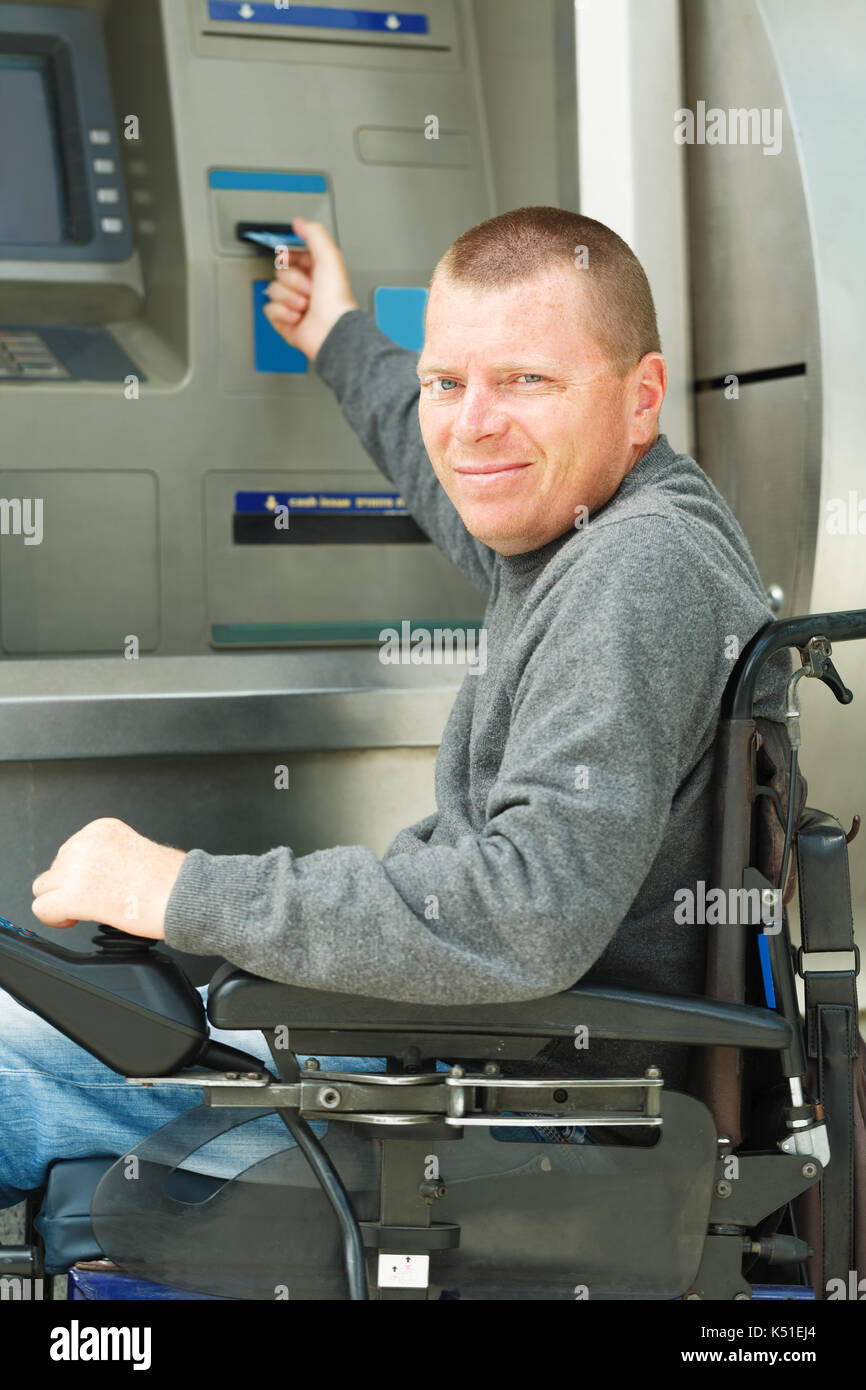 Behinderte Menschen stellen seine Kreditkarte am Geldautomaten. Stockfoto