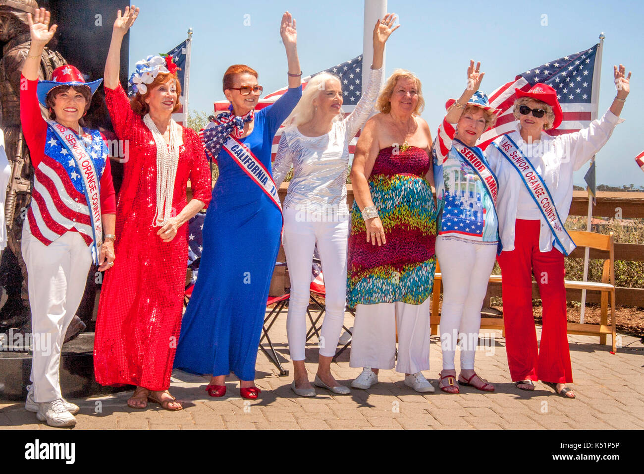 Unterstützt von US-Flaggen, kostümierte ältere Frauen Welle bei einem Viertel des Juli patriotischen Pageant in Newport Beach, CA, Park. Sie sind Mitglieder der 'Senior' Organisation. Stockfoto