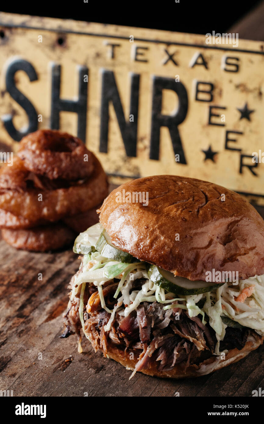 Südliche Texas style BBQ zog Pork Sandwich mit bleu Käse slaw und Dill Pickles auf rustikalen Hintergrund Stockfoto