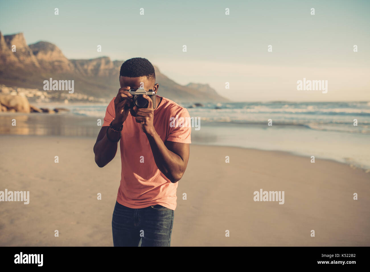 Afrikanischer Mann die Bilder mit digitalen Kamera am Strand. Junger Mann nimmt an der Küste. Stockfoto
