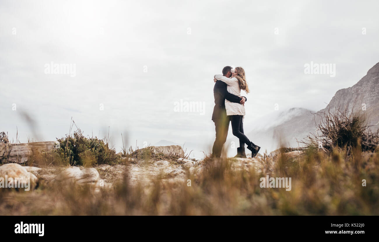Schönes Paar im Winter Kleidung umarmen am Strand. Romantische junge Paare auf Winter Urlaub am Strand. Stockfoto