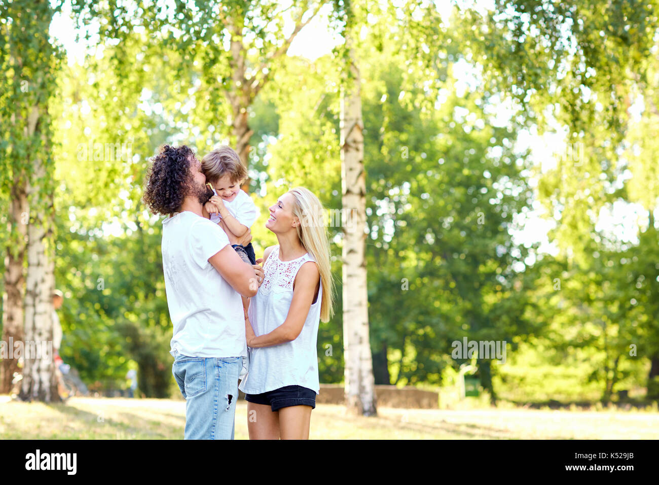 Mutter und Vater umarmt ein Kind im Park im Sommer. Stockfoto Mutter und Vater umarmt ein Kind im Park im Sommer. Stockfoto