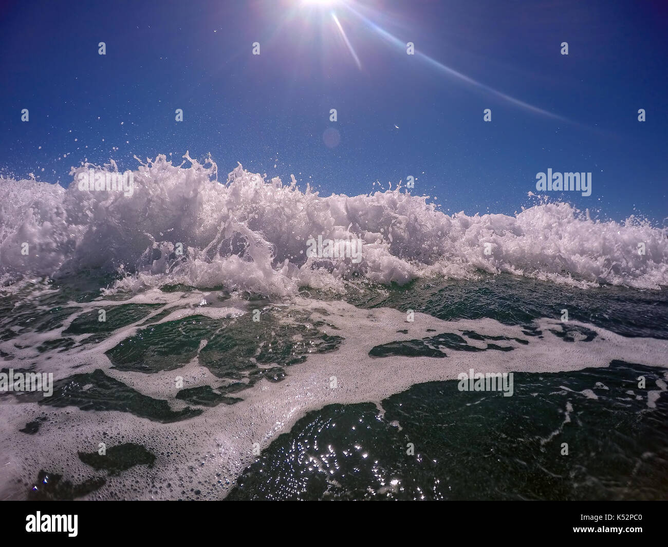 Ocean Wave brechen gegen den blauen Himmel. Absturz brechende Welle viel Spray und weißer Schaum. Stockfoto