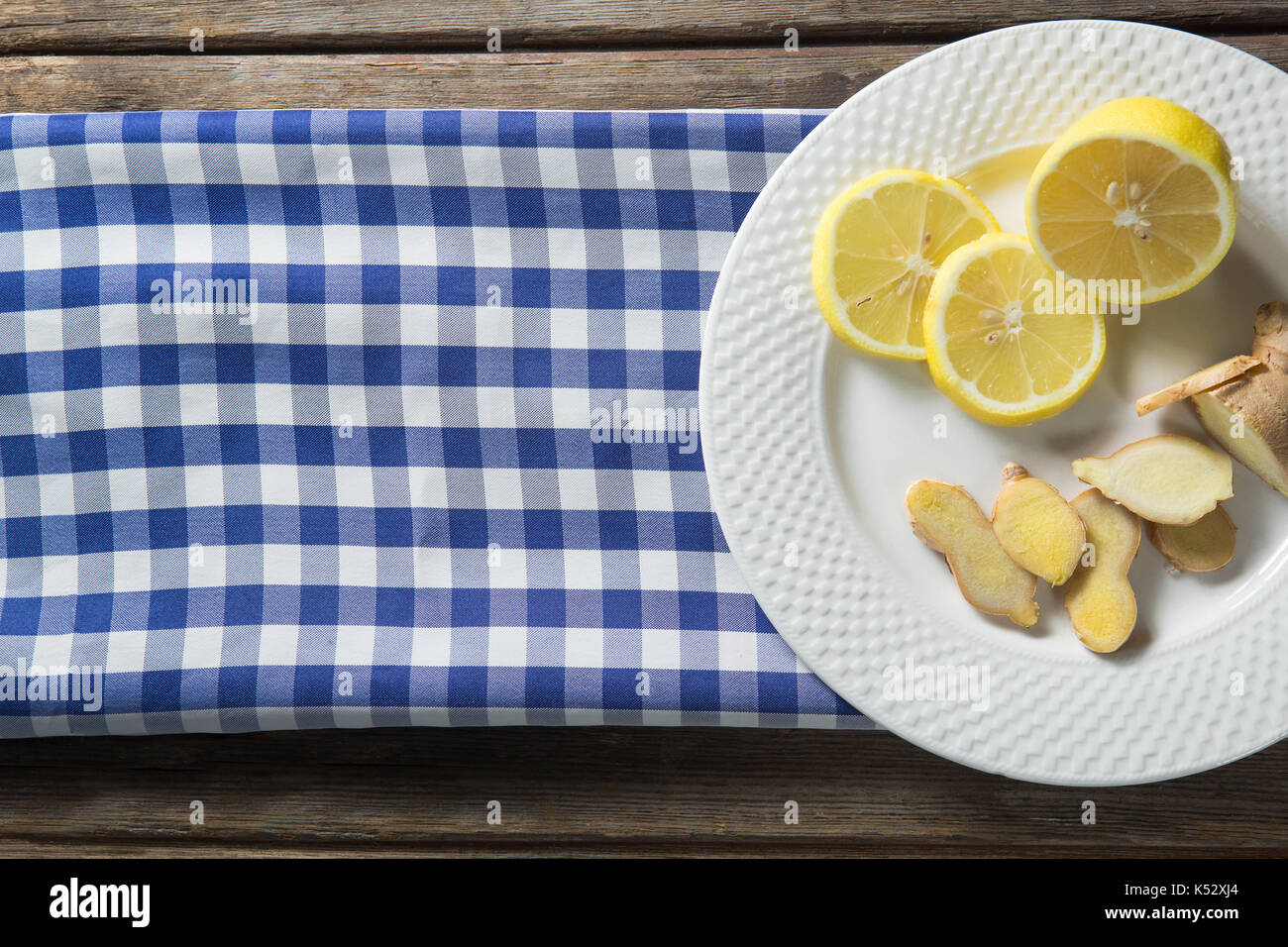 Ansicht von oben von Zitrone und Ingwer in der Platte mit gemusterten Serviette auf dem Tisch Stockfoto