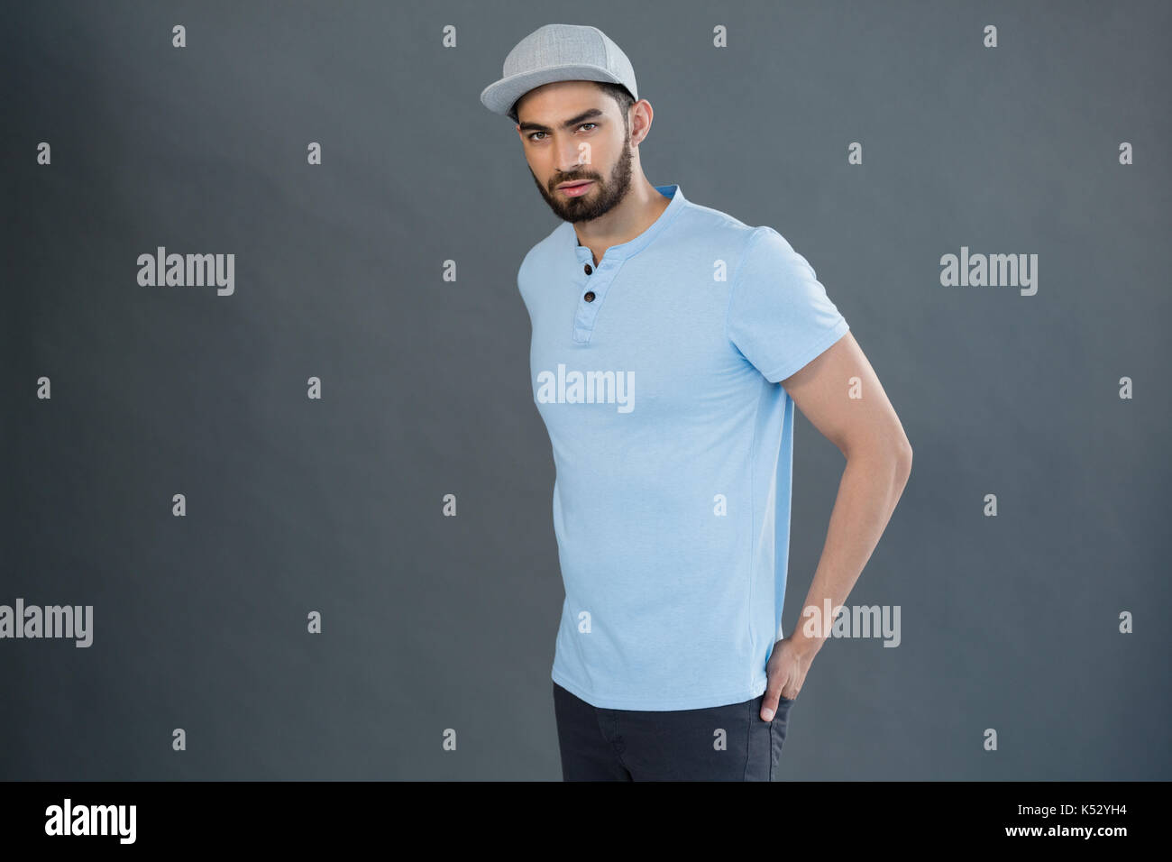 Portrait von stattlicher Mann mit den Händen in der Tasche gegen grauen Hintergrund posiert Stockfoto