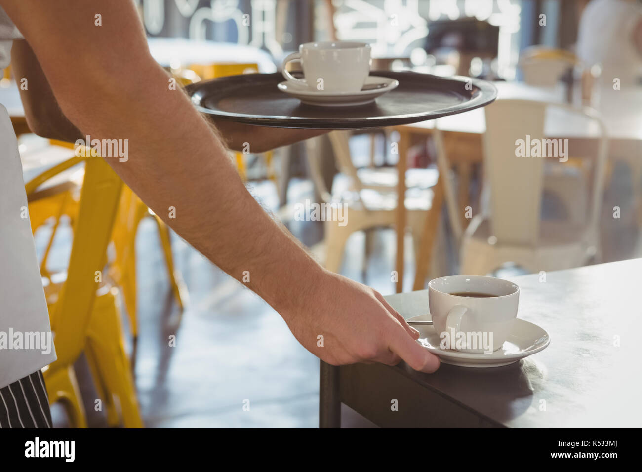 7/8 Hand der Kellner mit Kaffee auf Tisch im Cafe Stockfoto