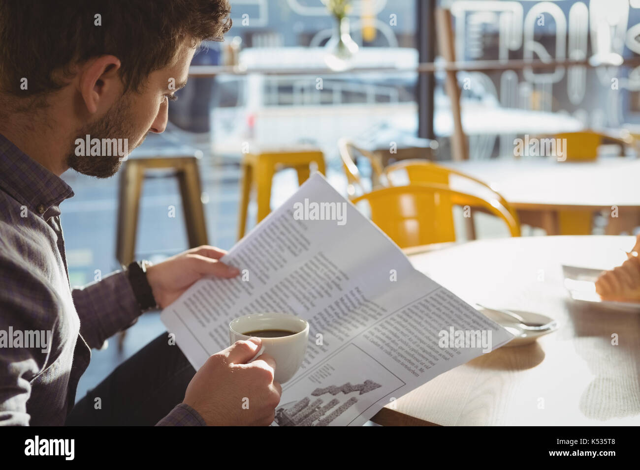 Junge Unternehmer/in beim Lesen der Zeitung im Cafe Stockfoto