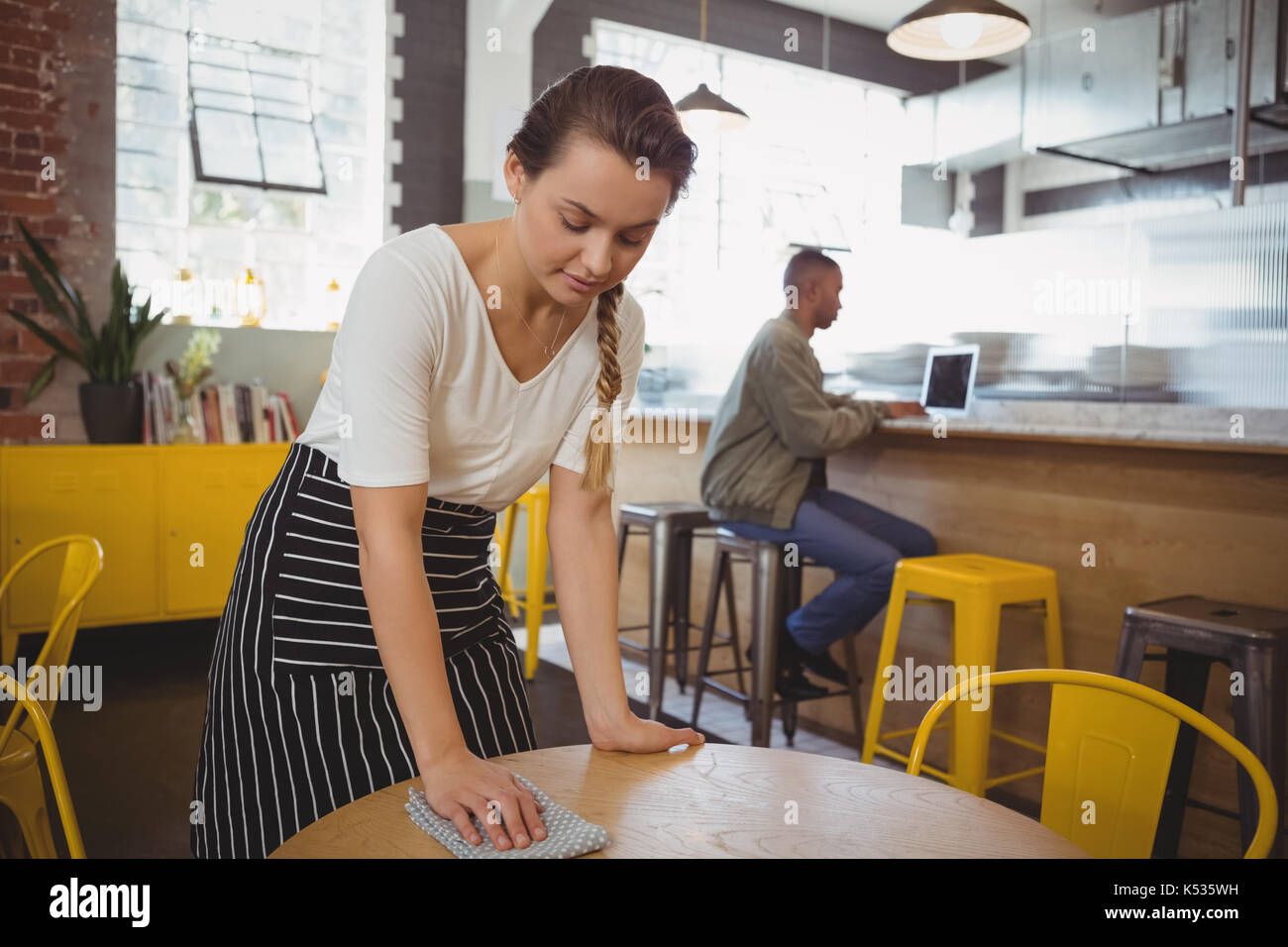 Junge Kellnerin Reinigung Tisch im Cafe Stockfoto