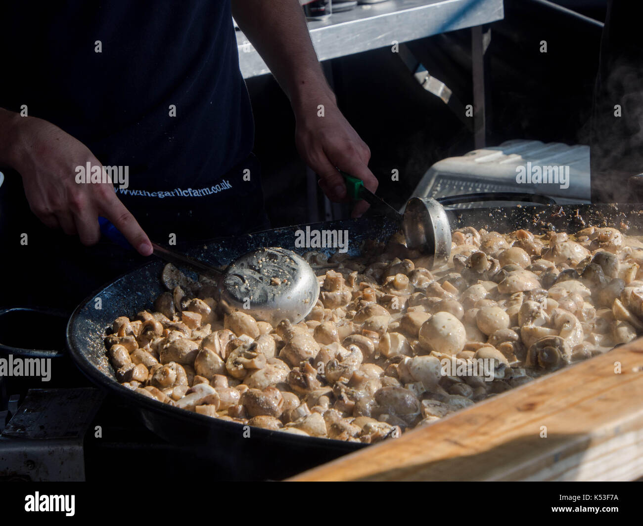 Ein Koch auf ein Essen in einer Straße Marktstand macht Knoblauch Pilze Stockfoto