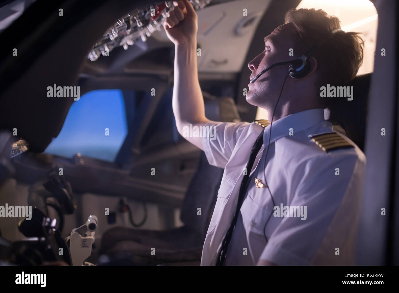 Junge männliche Pilot Kontrolle im Flugzeugcockpit aus dem Fenster gesehen Stockfoto