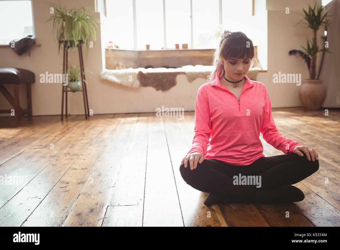Junge Frau meditieren auf Parkett im Studio Stockfoto
