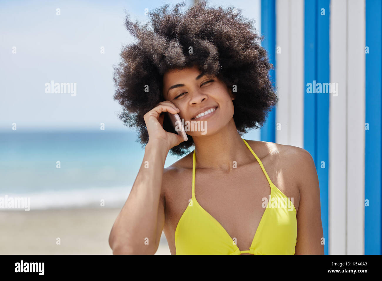 Portrait von ziemlich afro-amerikanische Frau im gelben Bikini sprechen auf mobilen Stockfoto