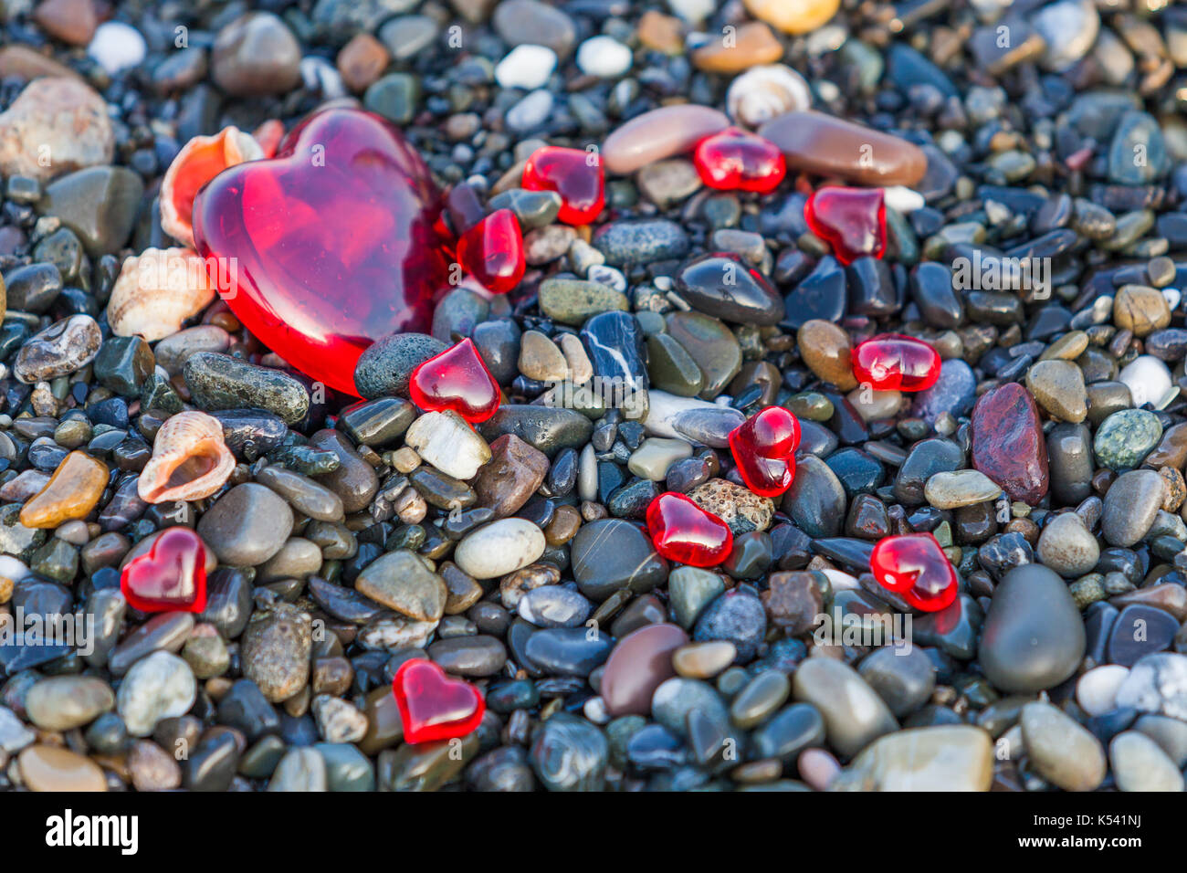 Kieselsteine am Strand. Hintergrund von Meer Steine Steine mit Herzen. Rotes Herz der Steine Stockfoto