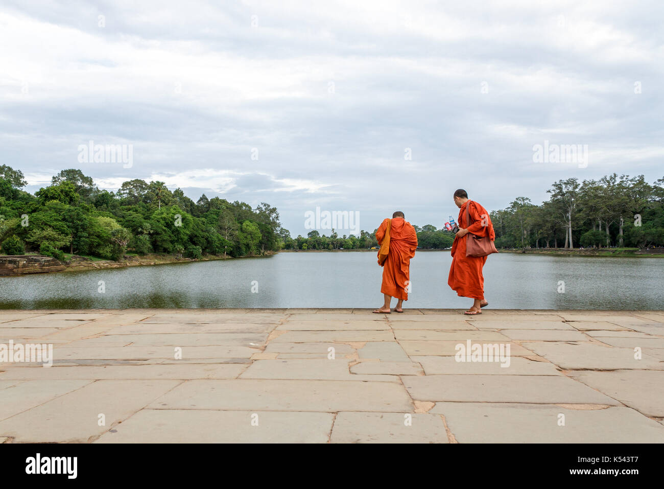 SIEM REAP, Kambodscha - 6/26/2015: Zwei Mönche zu Fuß über den Sandstein Causeway in Richtung West Gate von Angkor Wat. Stockfoto