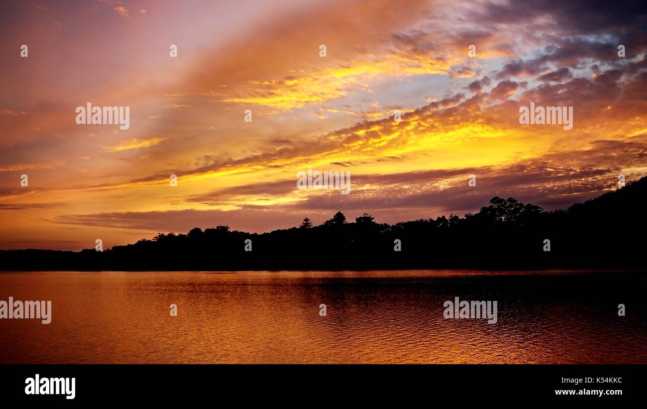 Eine malerische lebendige bewölkt Golden sunrise Marine aus dem Meer in Richtung der australischen Ostküste Festland suchen fotografiert. Eine inspirierende Szene. Stockfoto
