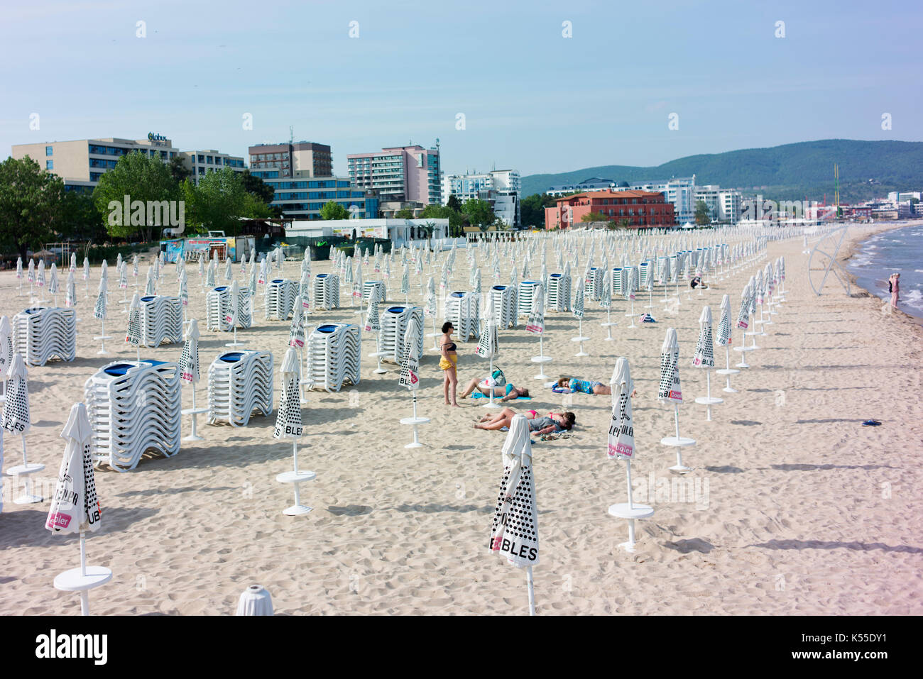 Menschen nehmen Sie ein Sonnenbad auf einer fast leeren Strand am sonnigen Strand gut vor der Saison. Stockfoto