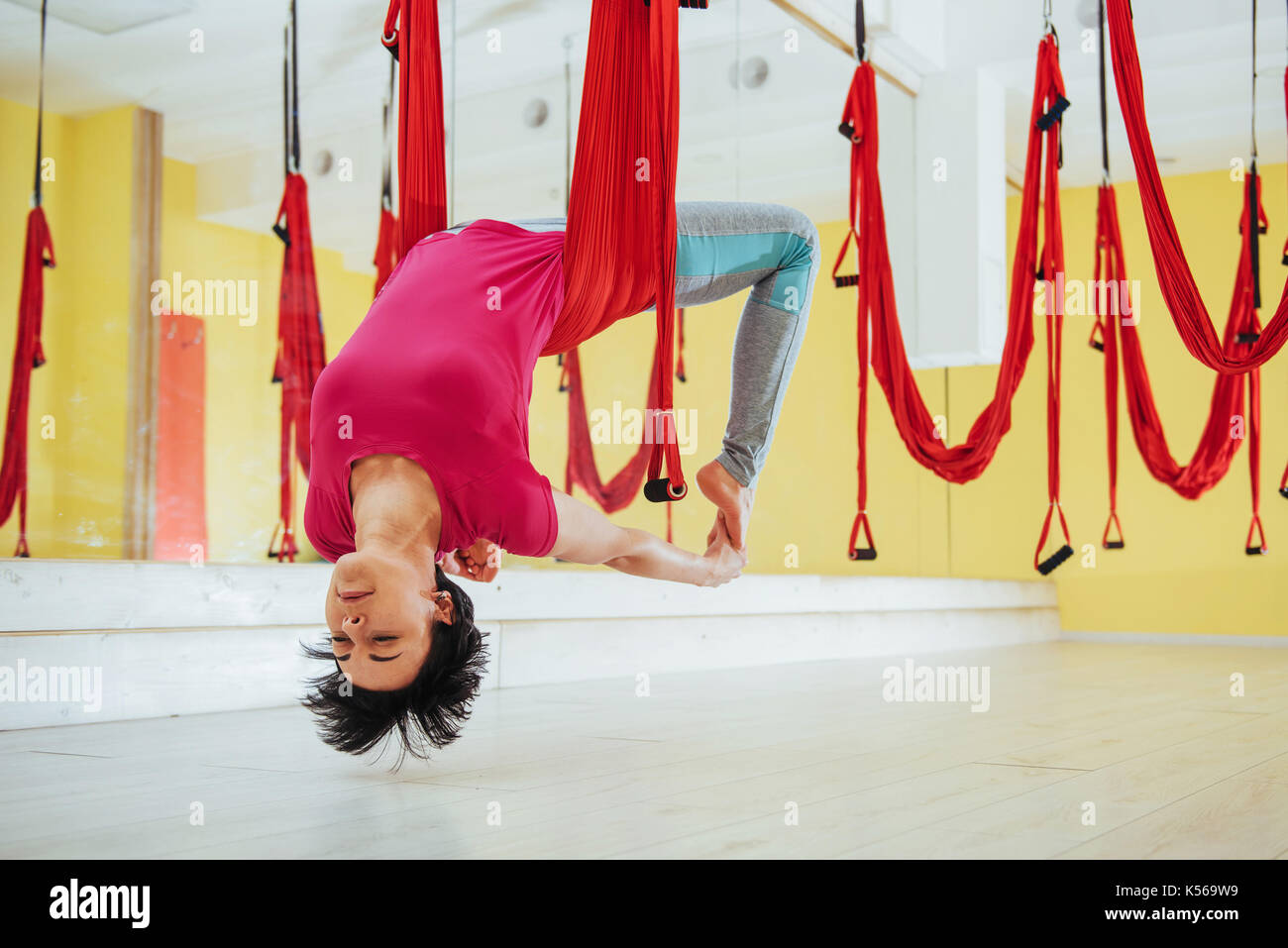 Junge schöne Frau Yoga mit einer Hängematte im hellen Studio Fliegen. Das Konzept der mentalen und physischen Gesundheit. Stockfoto