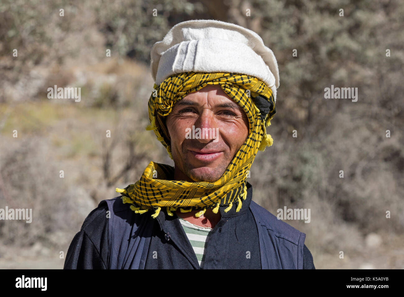 Close up Portrait von lächelnden Pamiri/Badakhshani Mann mit traditionellen Kopfbedeckungen, Provinz Gorno-Badakhshan, Tadschikistan Stockfoto