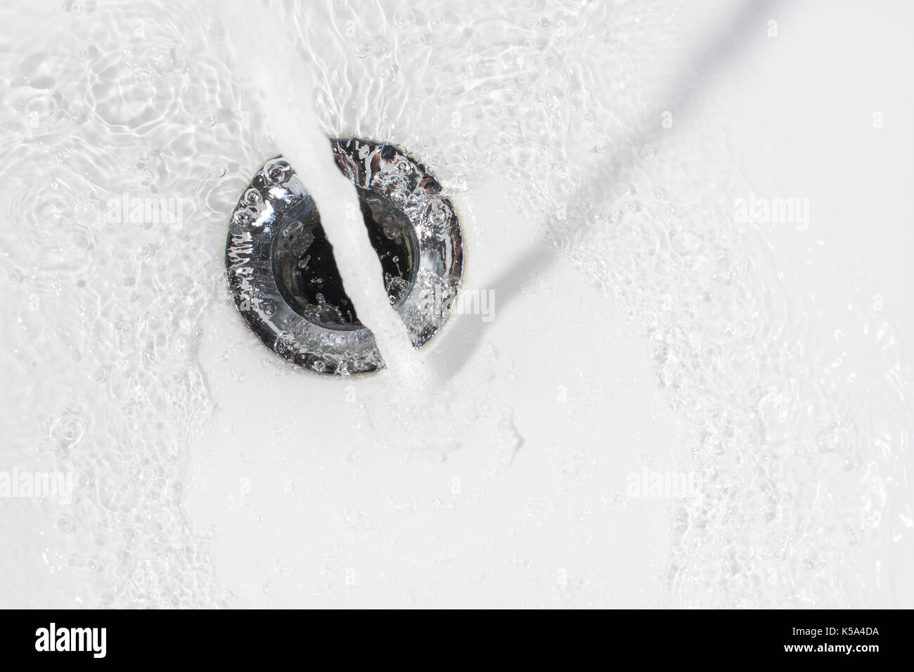 Frisches Wasser in den Abfluss eines keramischen Waschbecken Stockfoto