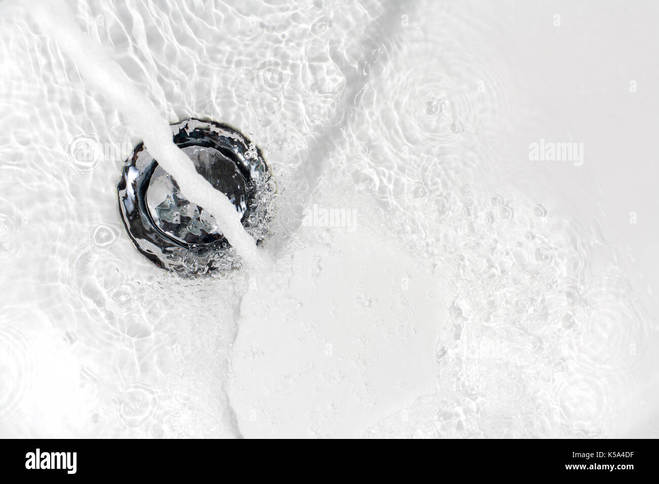 Frisches Wasser in den Abfluss eines keramischen Waschbecken Stockfoto