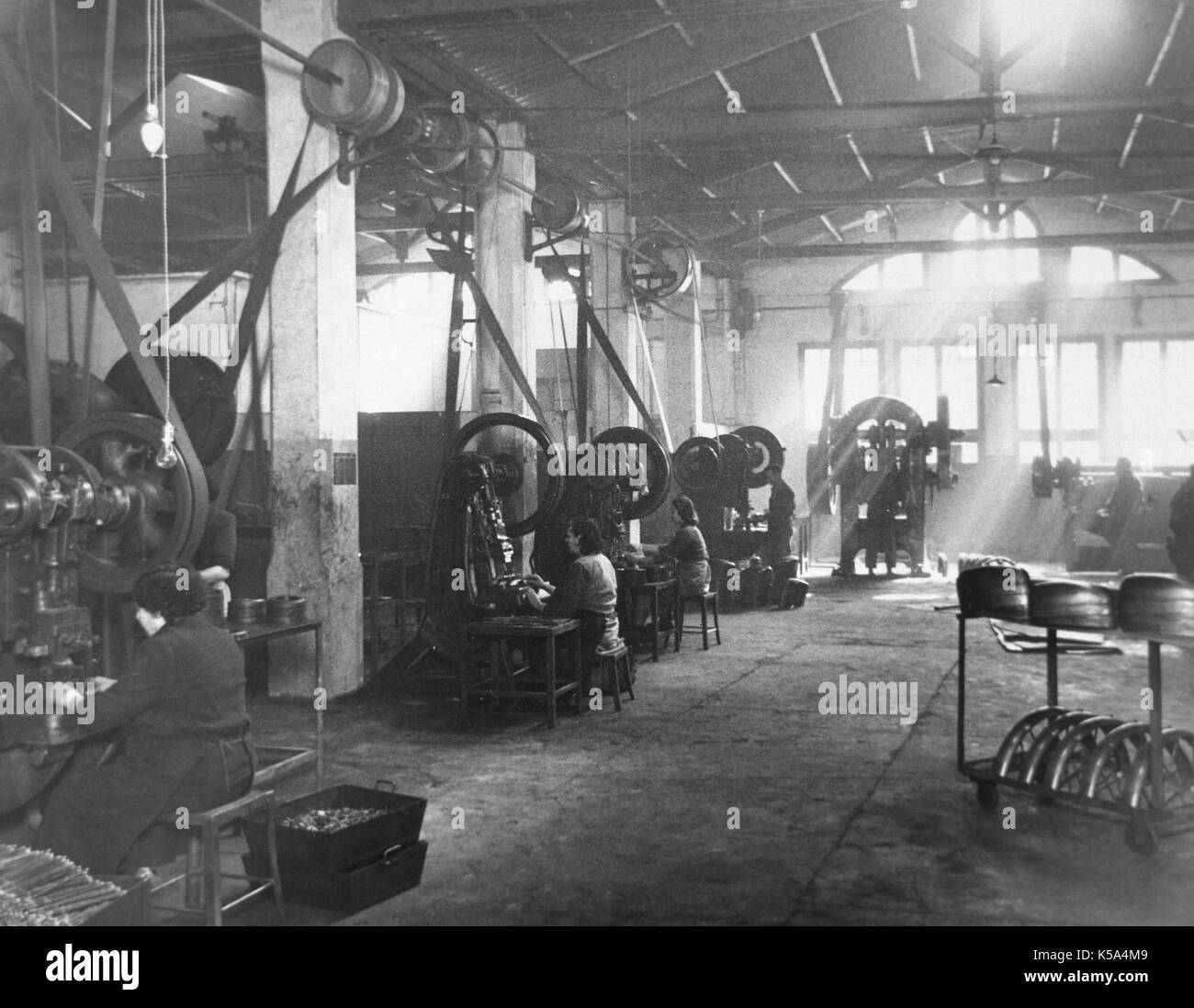 Die spanische Industrie, 1945. Kette der Arbeit der Fabrik der Motorrad- Komponenten. Abschnitt von Pressen. Maschinen, die mit einer Riemenscheibe System angetrieben. Barcelona, Katalonien, Spanien. Stockfoto