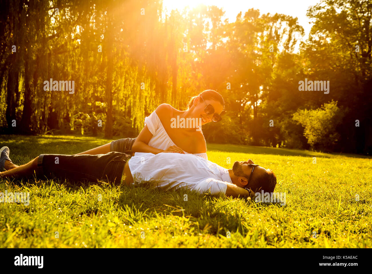 Eine schöne, junge Paare mit in das Gras in einem Park im Sonnenuntergang Stockfoto