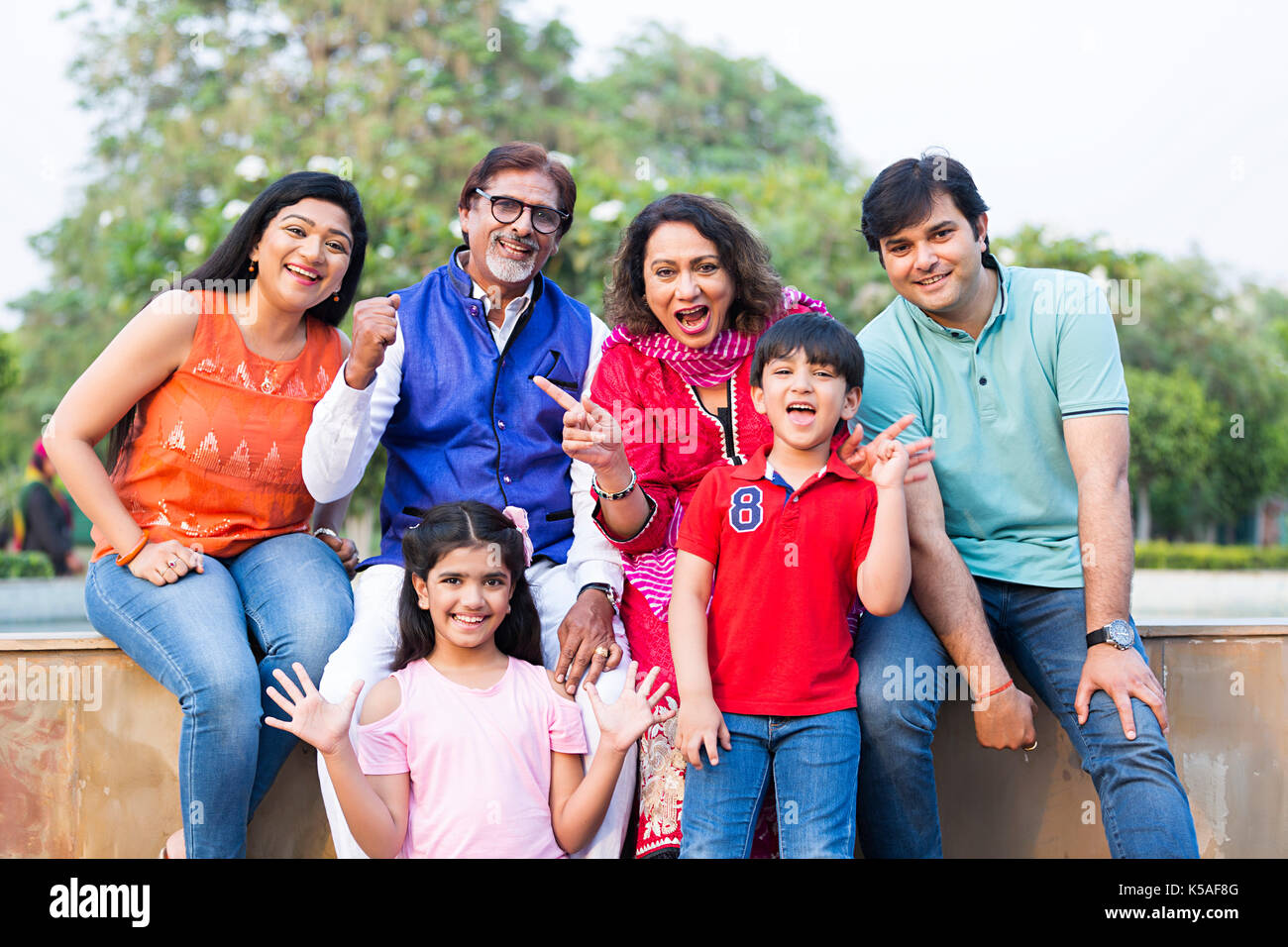 Indische große Familie sitzen Mauer Park Spaß lächelnd Wochenende Urlaub Stockfoto