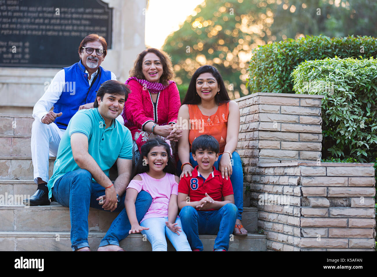 Indische große Familie sitzen Treppen Park genießen lächelnd Wochenende Urlaub Stockfoto
