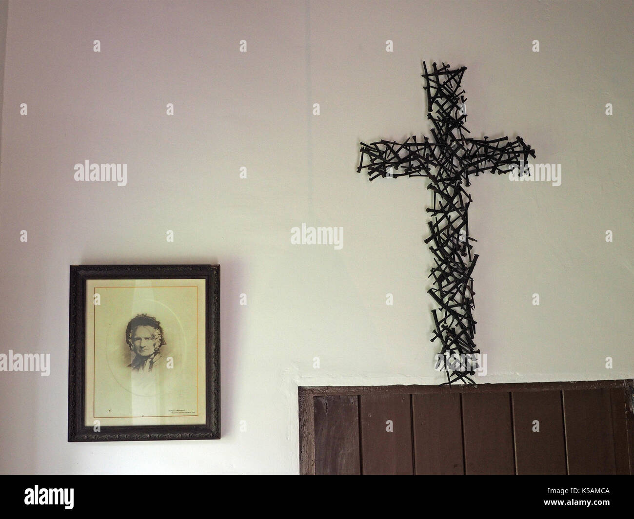 Schmiedearbeiten Kreuz neben Portrait von Margaret Heathcote, konzipiert und gebaut, Kirche der Heiligen Dreifaltigkeit in Grange-in-Borrowdale, Cumbria, England, Großbritannien Stockfoto