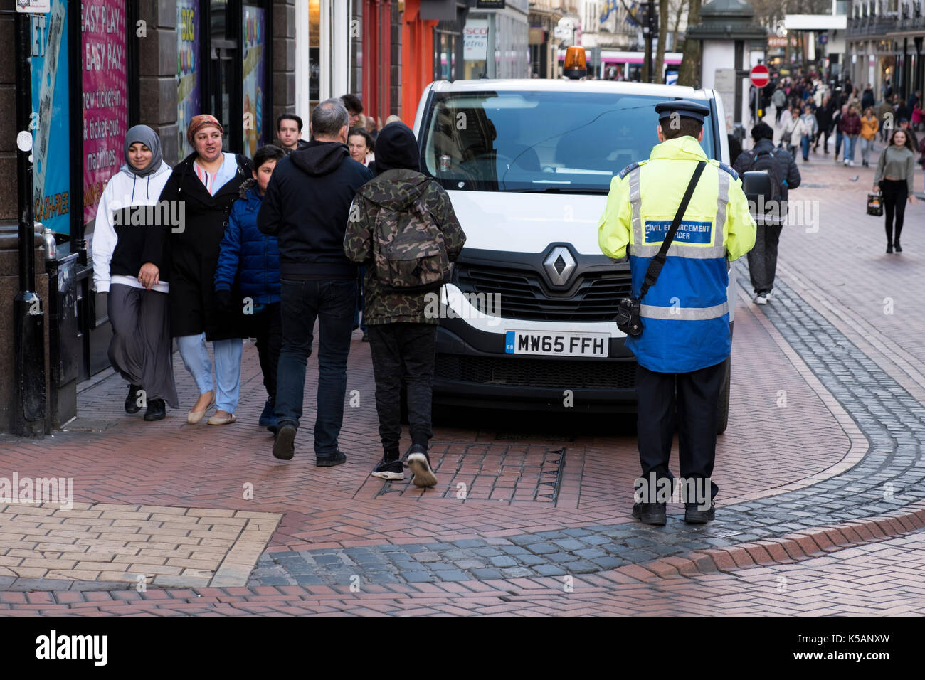 Ein Parkwächter, der für einen gemeinderat arbeitet, gibt einen aus Parkschein für einen Van, der illegal in einem geparkt ist City High Street Stockfoto