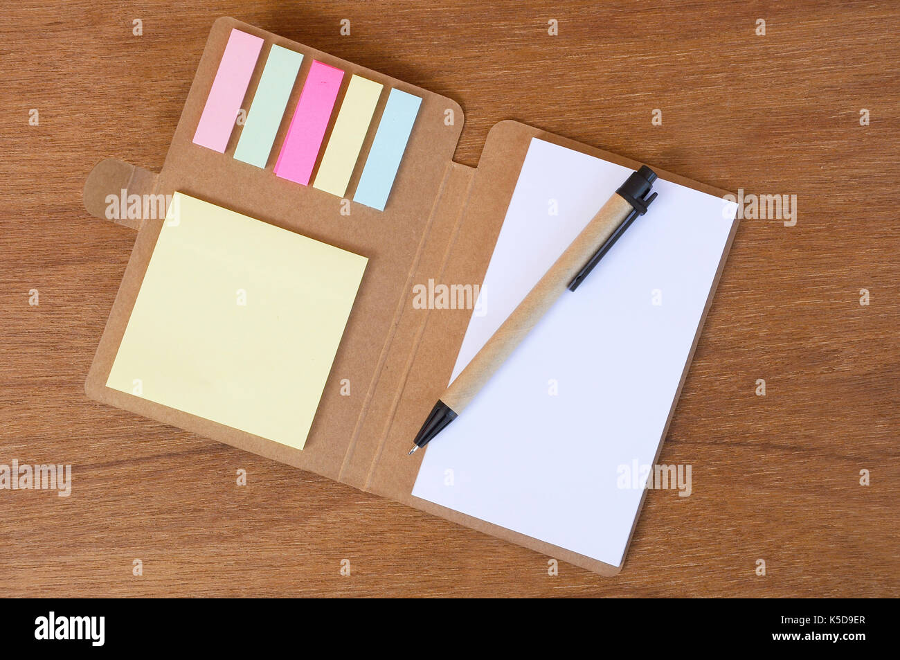 Braun pen, Notebook und bunte Zettel auf holzmaserung Hintergrund isoliert. Stockfoto