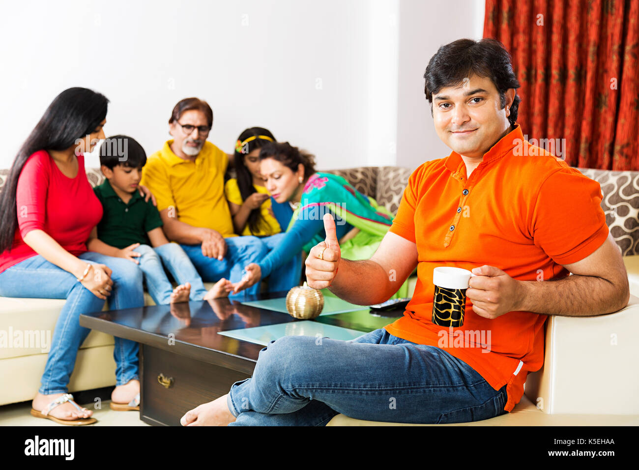 Glückliche Familie sitzt mit ihrem Mann Tee trinken thumbsup im Vordergrund Stockfoto