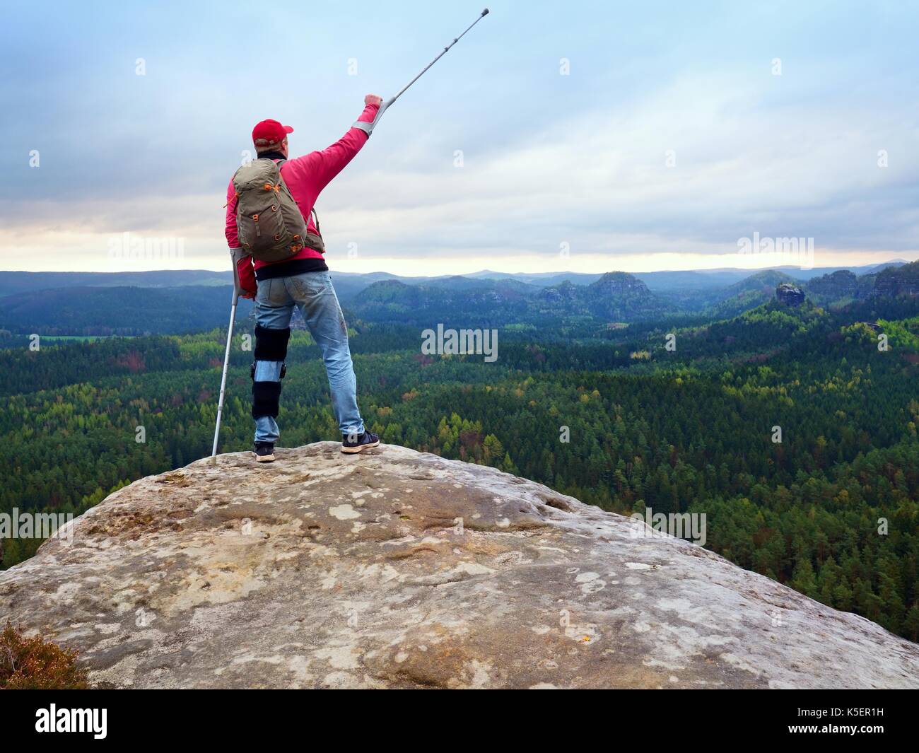 Peak Triumph. Mann mit Bein in Knie Käfige und Krücken für Stabilisierung und Unterstützung. Wanderer mit verstellbaren Seitenteile o Unterstützung zu sichern und Stockfoto