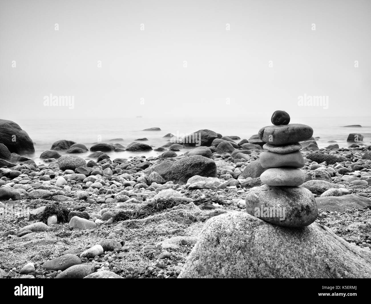Ausgewogene Stein Pyramide am Meer, Wellen im Hintergrund. Bunte flache Steine für die Meditation am Meer Stockfoto
