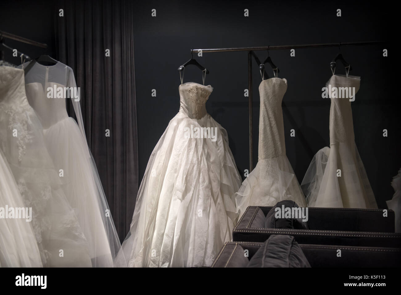 Auswahl der weiße Brautkleider und Ballkleider auf Anzeige hängen auf Schienen mit selektiven Fokus auf einer beleuchteten durch ein Highlight Stockfoto
