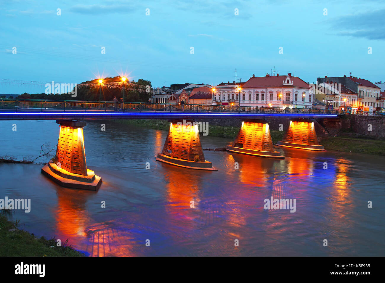 Beleuchtete Fußgängerbrücke in das Zentrum von Uzhgorod am Abend, Ukraine Stockfoto