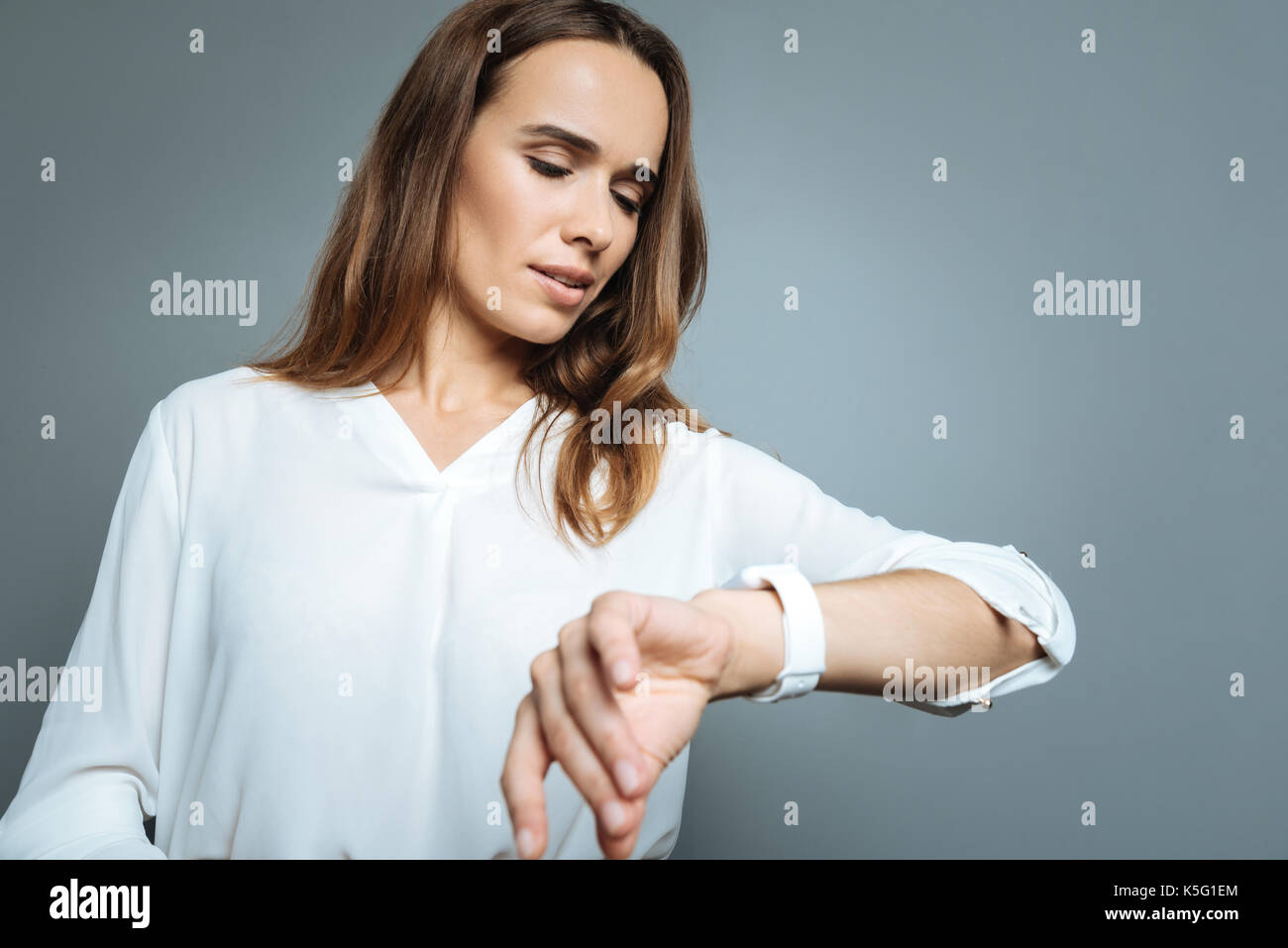 Ernsthafte beschäftigte Frau, die die Zeit zu wissen, Stockfoto