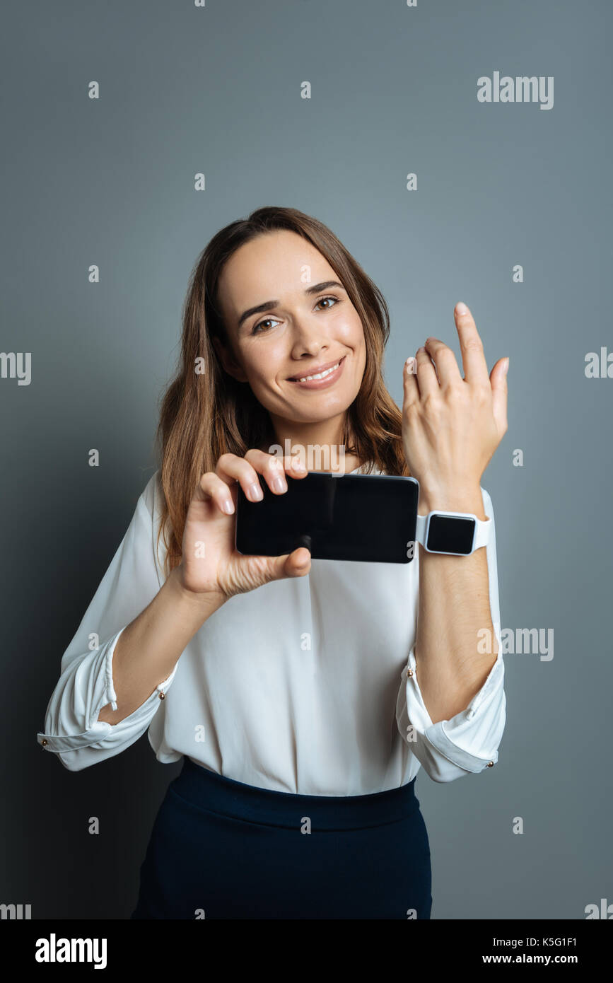 Positiv erfreut, Frau, ihr Smartphone Holding Stockfoto