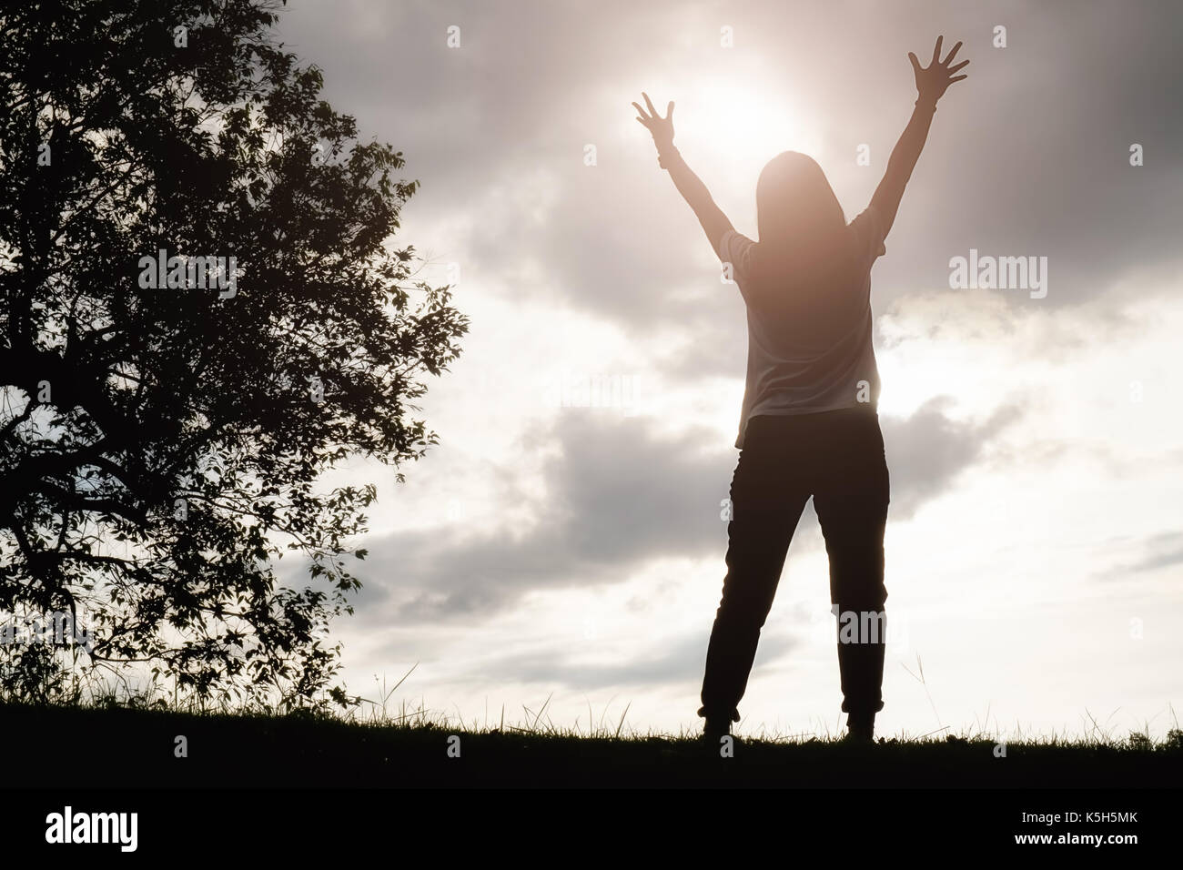 Ein glückliches asiatische Frau ist entspannend auf grünem Gras und angehoben bis zu Sky Arme auf sonnigen Sommertag mit Park Hintergrund. Konzept von Wohlbefinden und gesunde l Stockfoto