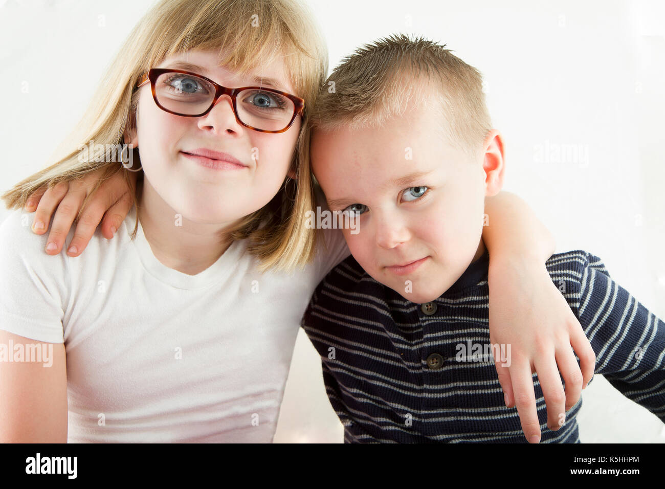 Zwei junge Kinder umarmen einander whiel in die Kamera schaut Stockfoto