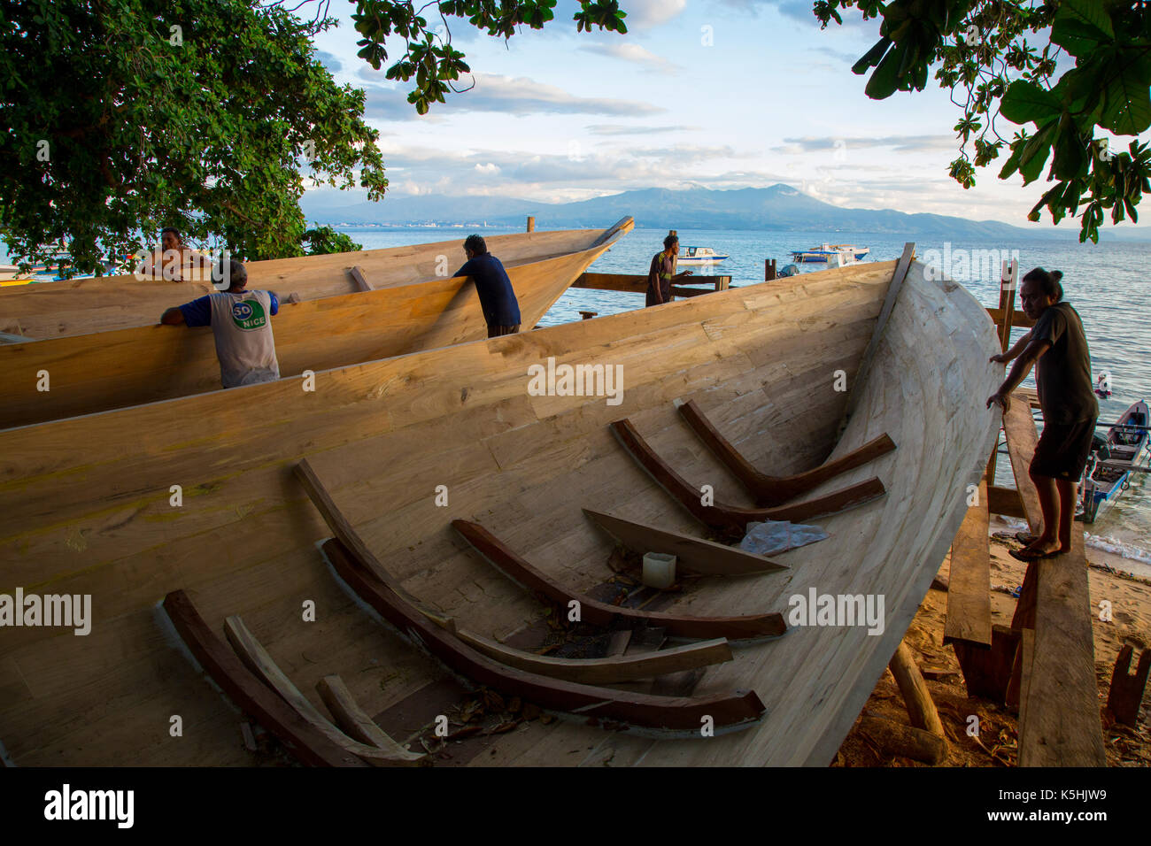 Bootsbauer beobachten ihre Arbeit am Strand von Bunaken Insel Sulawesi Stockfoto