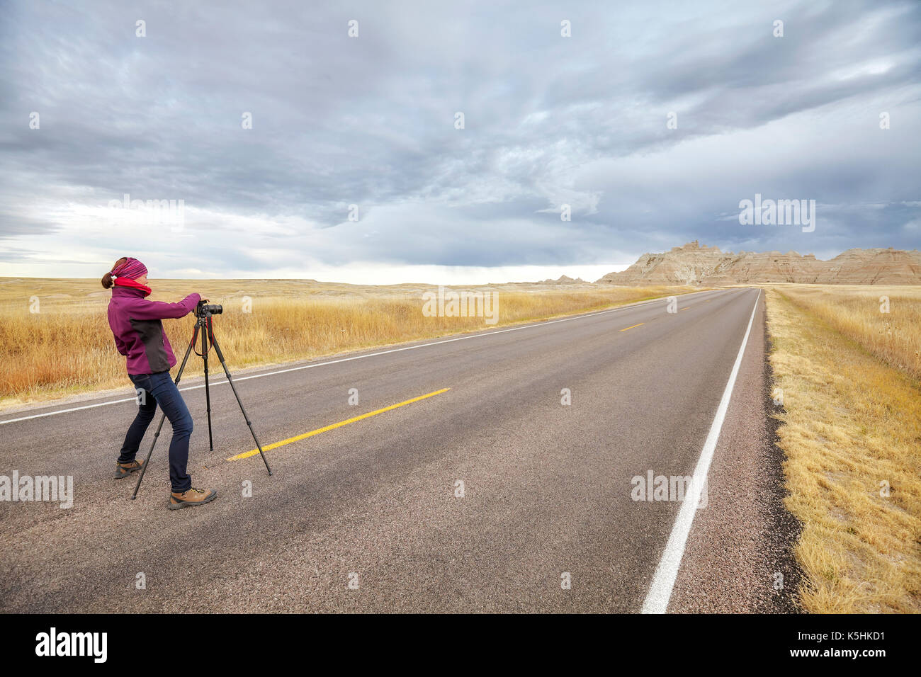Landscape Photographer nimmt Bilder auf einer leeren Straße mit stürmischen Himmel, Reisen oder Arbeiten Konzept, Badlands National Park, South Dakota, USA. Stockfoto